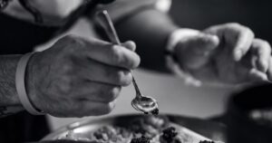 Chef plating a course in a restaurant kitchen. Business and Lifestyle, GCC Media.