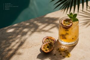 Passion fruit margarita in a fluted glass on limestone beside a pool, halved passion fruit alongside. Hospitality, GCC Media.