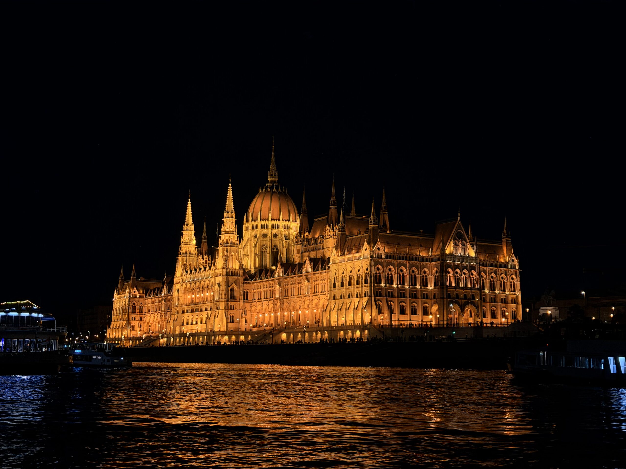 Hungarian Parliament Building illuminated at night beside the Danube in Budapest